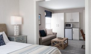 One Bedroom Luxury Suite in Edgartown, MA with Kitchenette Space with White Cabinets, King Bed with White Sheets and Lounge Area with Gray Couch